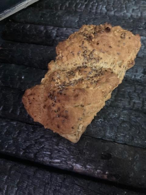 A seeded loaf of bread on a dark wooden table